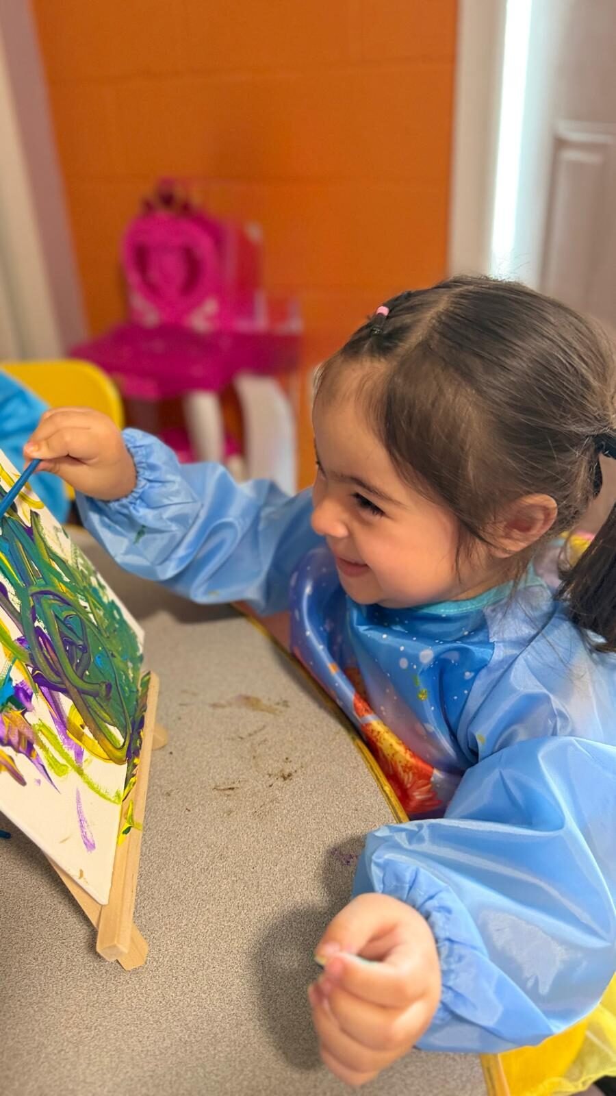 Niña pintando con témpera en un caballete
